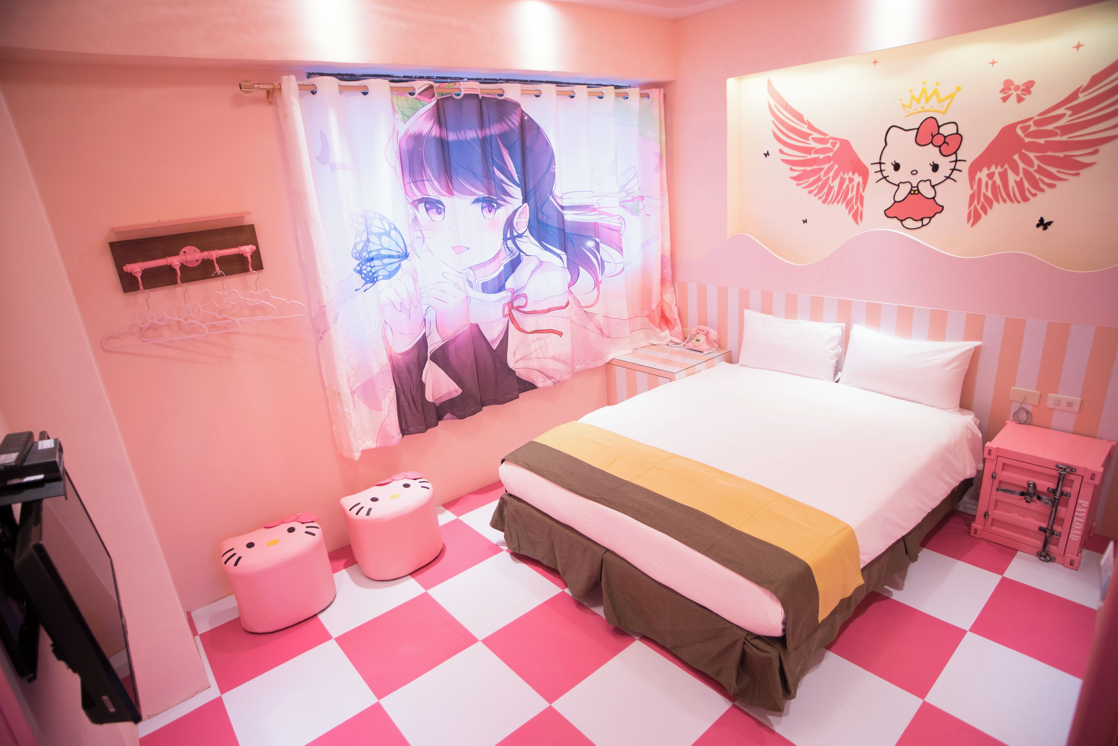 A pink-themed bedroom with a bed, a vanity, and a Hello Kitty wall decoration.