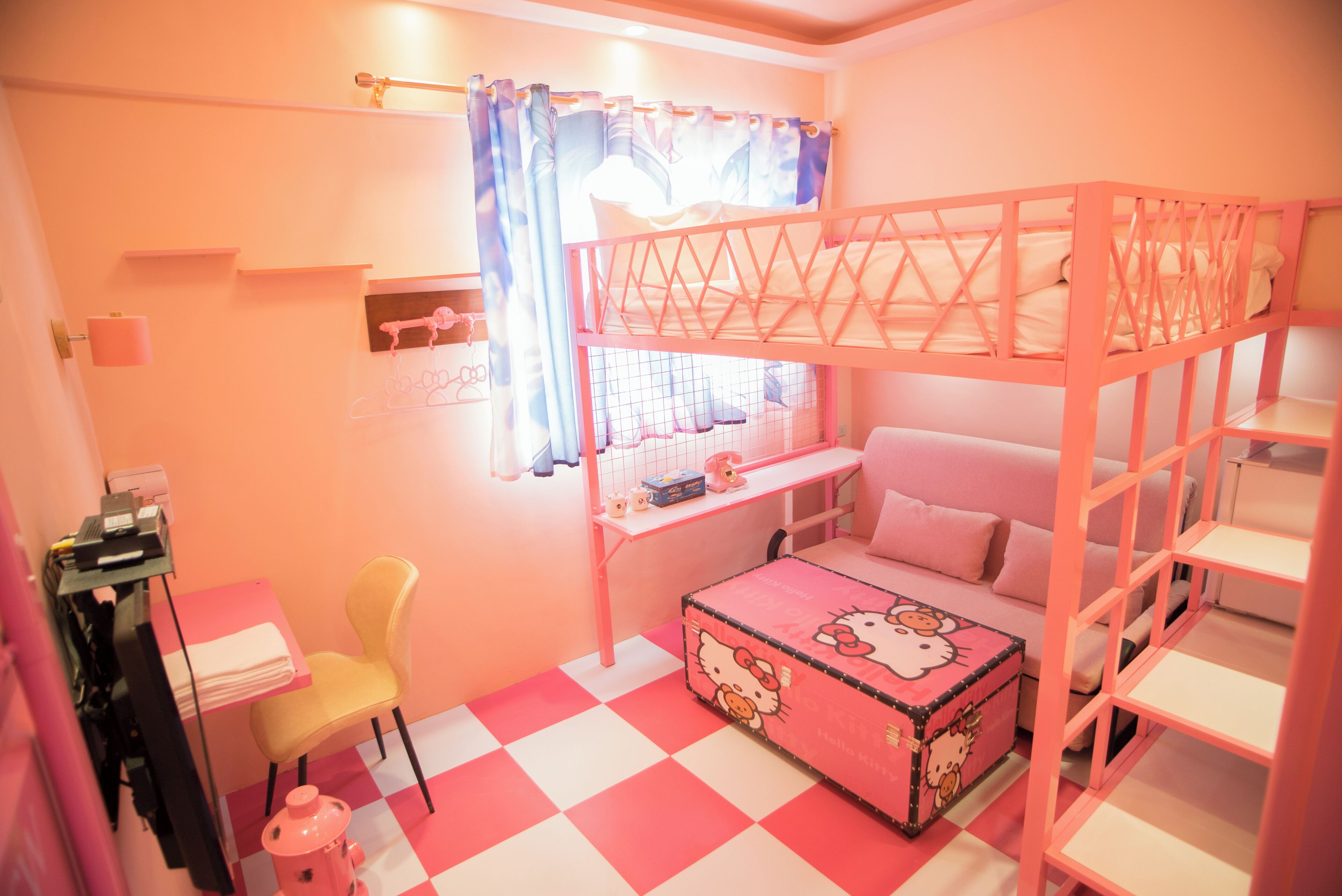 Una habitación infantil decorada en tonos rosas, con literas, un escritorio y una silla.
