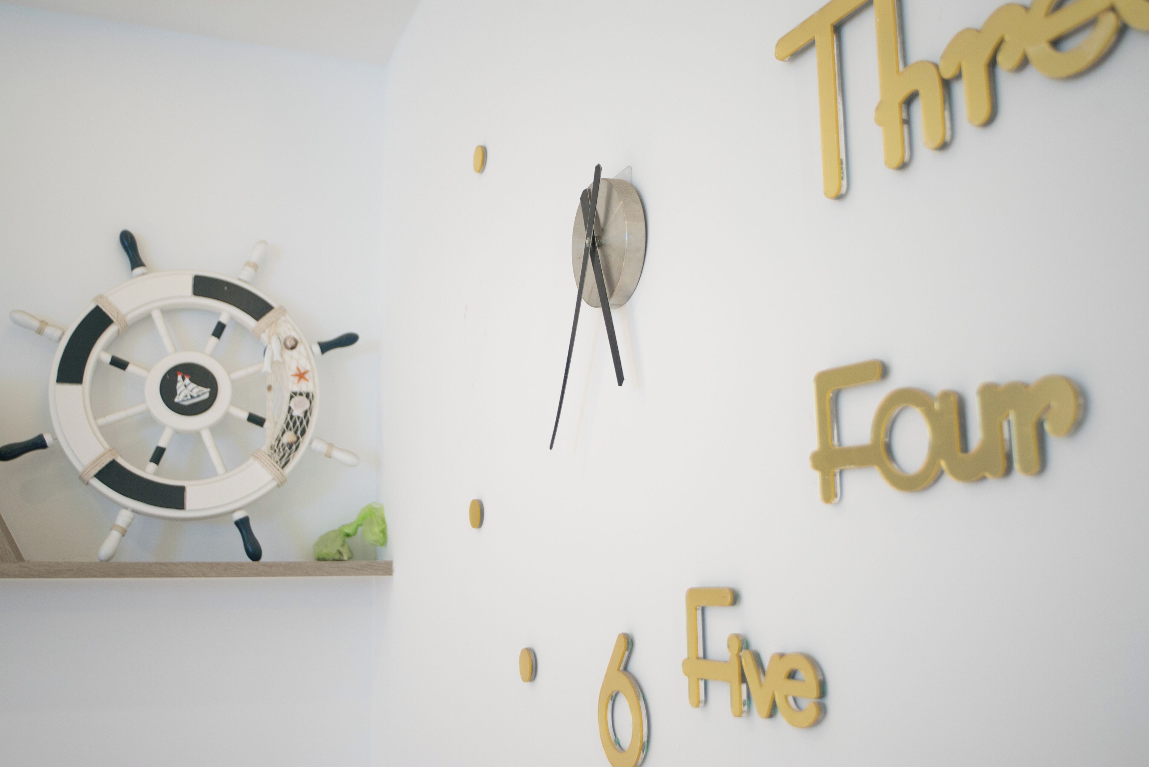 A wall with a ship's wheel and gold letters spelling 'Three Four Six'.