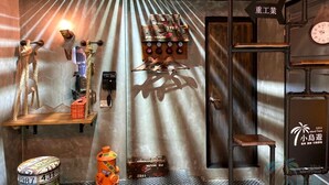 A room with a metal ceiling, a wooden shelf with shoes, a clock, and a sign with Chinese characters. - Hexing Hotel (Magong)