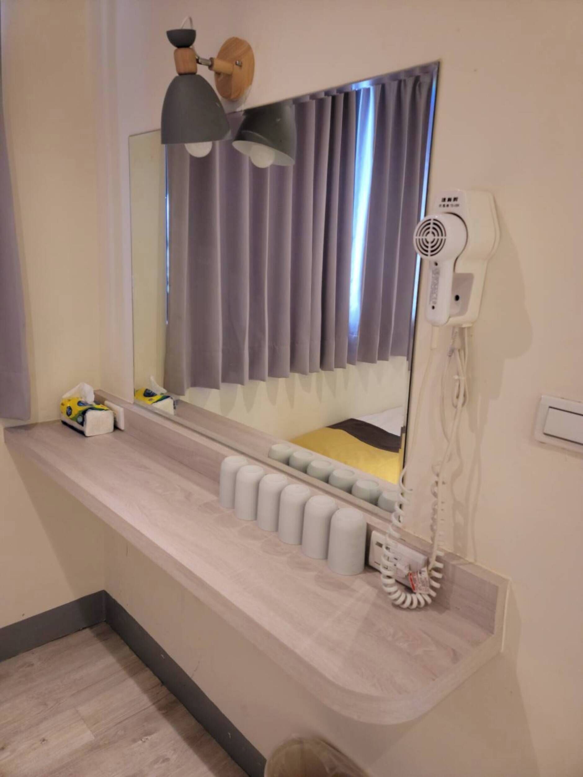 Un baño moderno con tocador, un espejo grande, secador de pelo y un perchero para toallas.