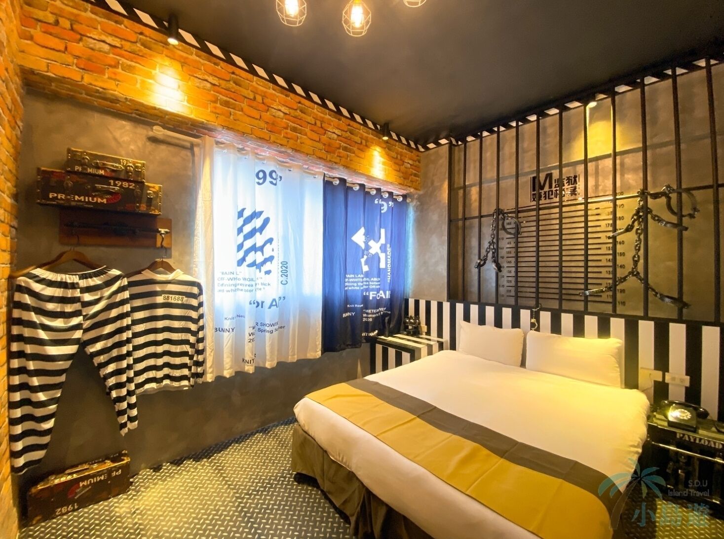 Une chambre d’hôtel avec un lit, un fauteuil suspendu, une petite table et un mur muni d’une étagère en métal.