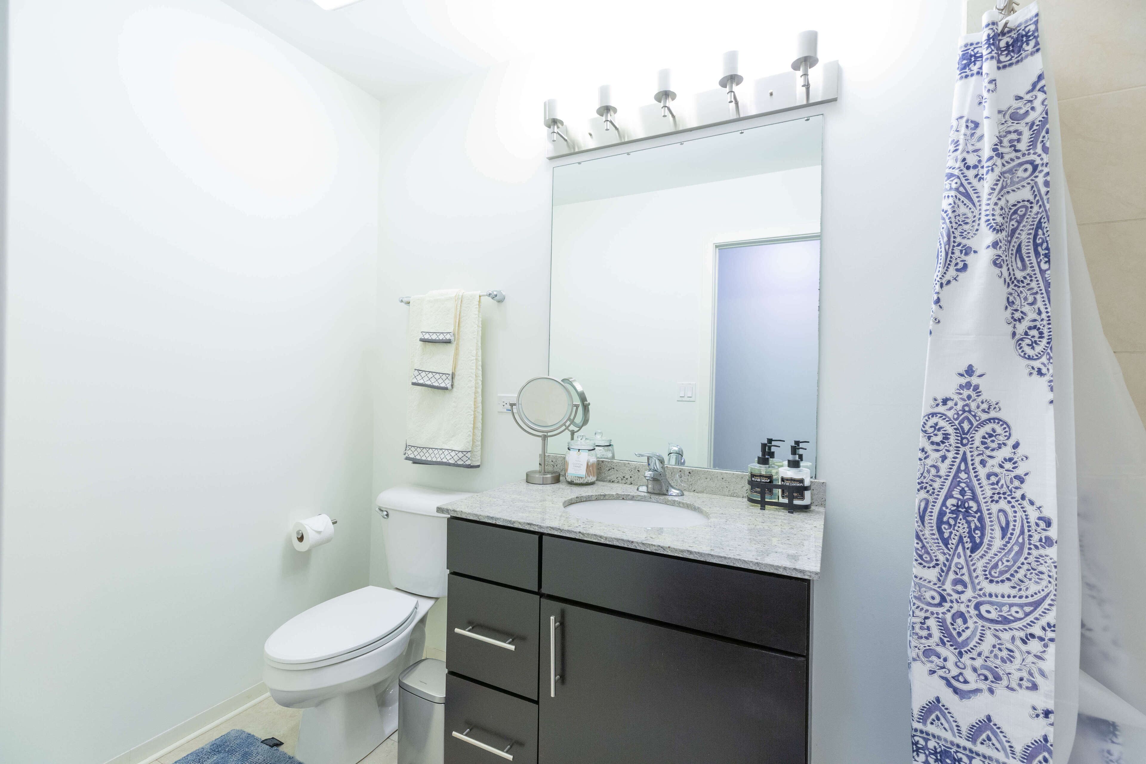 Une salle de bain équipée de toilettes, d’un lavabo, d’un miroir et d’un meuble-lavabo.