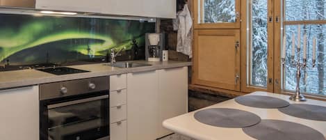 A modern kitchen with a built-in oven, a coffee maker, and a view of the aurora borealis through a window.
