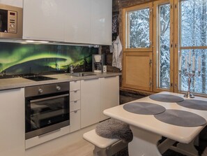 Eine moderne Küche mit Einbauofen, Kaffeemaschine und Blick auf das Polarlicht durch ein Fenster.