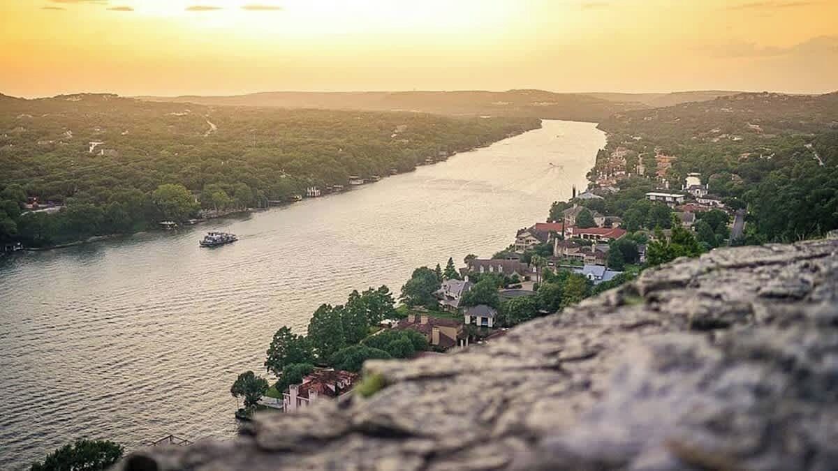 Een rivier met een boot, omringd door groen en gebouwen.