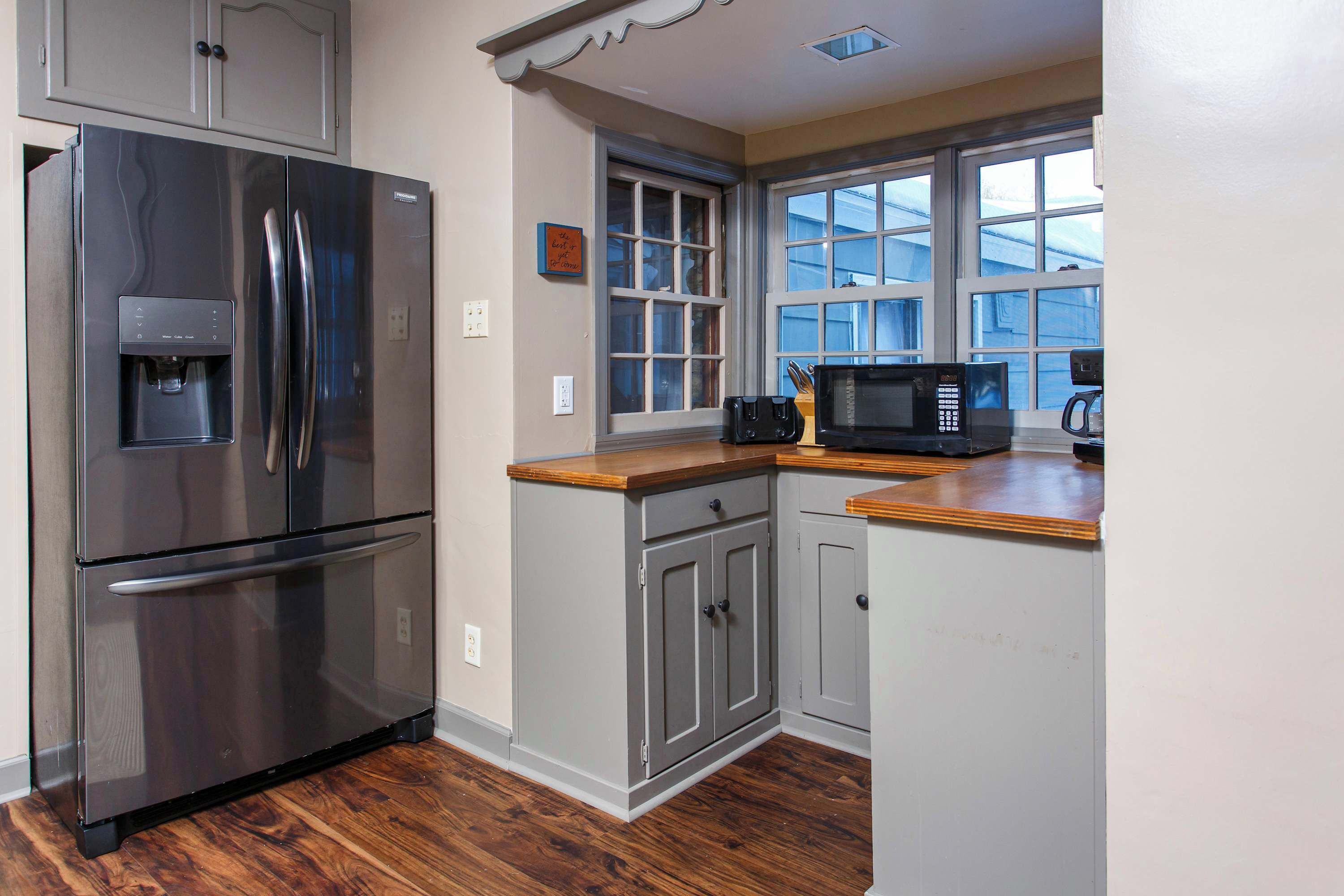 A kitchen with a stainless steel refrigerator, a microwave, and wooden countertops.