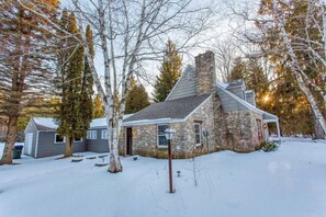 A stone house with a chimney, surrounded by trees and snow. - Manistique Stone Cottage - Next to Peninsula State Park (Fish Creek)