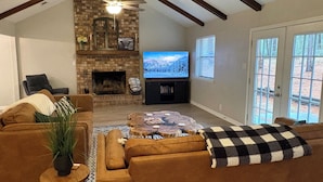 Una sala de estar con chimenea, televisor y un ventanal grande.