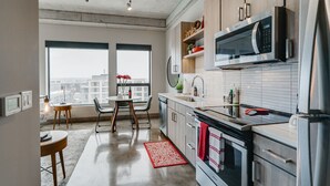 Cozinha moderna com uma janela grande, área de jantar com mesa e cadeiras, e vista para a cidade.
