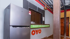 A kitchen area with a stainless steel refrigerator, a sign for 'KAUNTER PENDAFTARAN', and the 'OYO' logo. - OYO 89921 Motel New Bay Sg. Lembing (Sungai Lembing)
