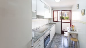 A compact kitchen with white cabinets, a granite countertop, a built-in oven, and a window with a view of greenery. - NAVEGANTE - Apartment with shared pool in Playa de Gandia. (Playa de Gandia)