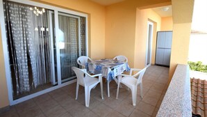 A balcony with a table and chairs, a sliding glass door, and a refrigerator. - Apartment Lucy with a Balcony (Vantačići)