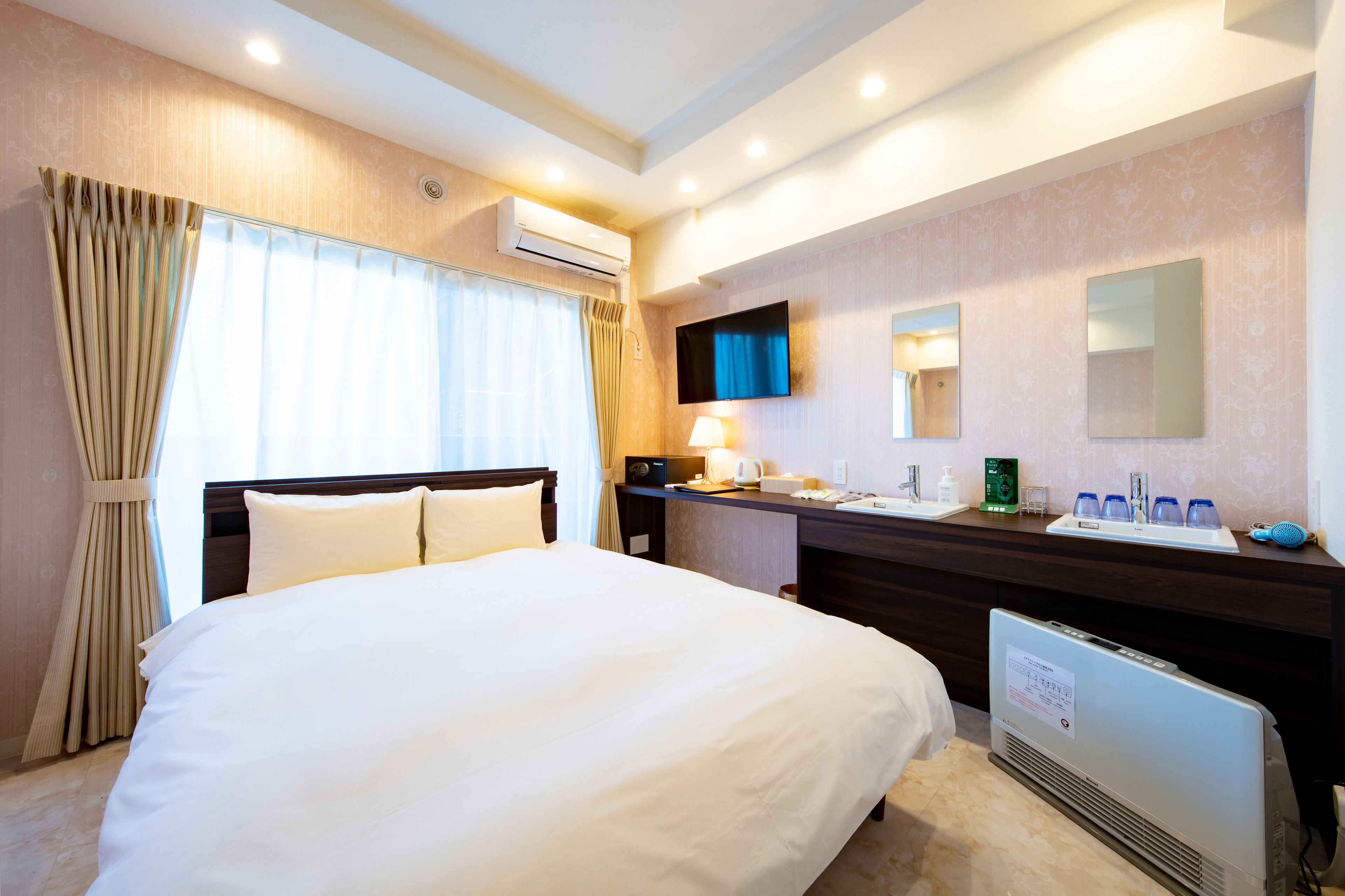 A hotel room with a large bed, a desk with a mirror, and a sink.