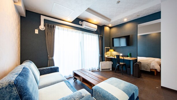 Una habitación de hotel moderna con sofá, escritorio, cama y televisor.