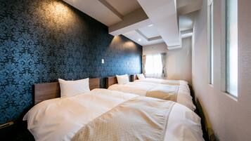 A hotel room with two beds, a patterned wallpaper, and a window with curtains.