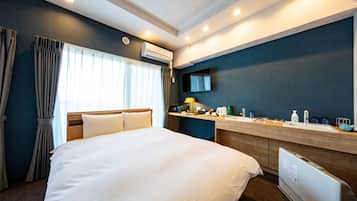 Habitación de hotel con una cama grande, un escritorio con lavamanos, un espejo y un equipo de aire acondicionado.