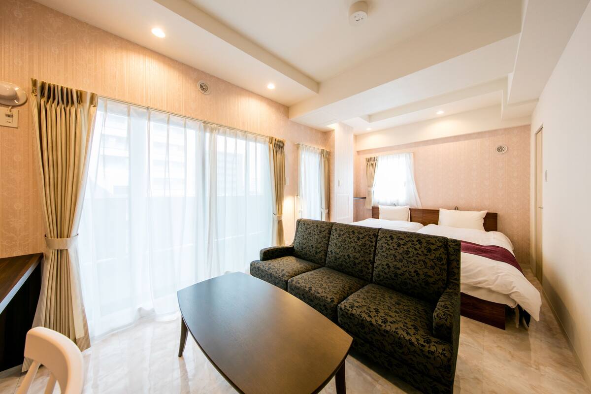 A hotel room with a sofa, a bed, a desk, and a chair.