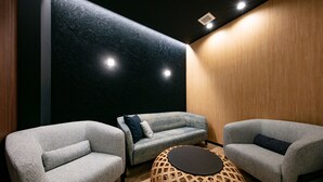 Un área de estar moderna con sofás grises, un revestimiento de pared de madera y una mesa redonda de madera.