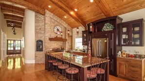 A spacious kitchen with a large island, dark wooden cabinets, and a brick accent wall.