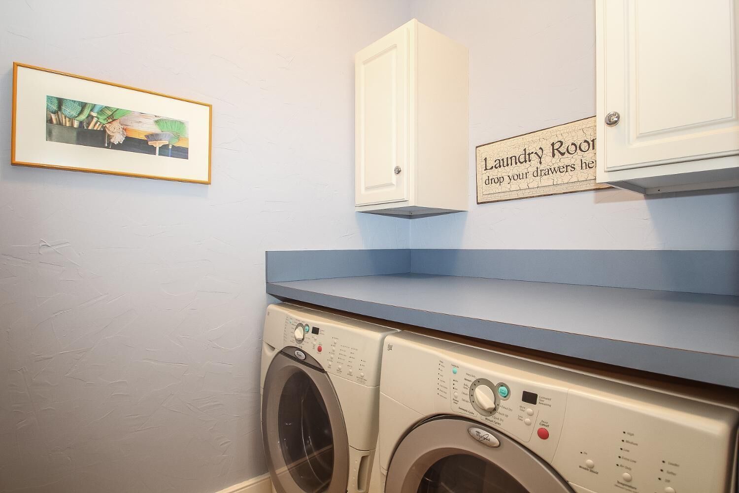 A laundry room with a washing machine, a drying rack, and a sign that reads "Laundry Room drop your drawers here."