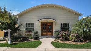 A two-story house with a front porch, a central entrance door, and a small front yard with a pathway leading to the door.