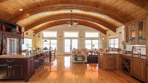 A spacious kitchen with wooden cabinets, a dining area with chairs, and a ceiling fan.