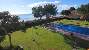 Una piscina con vista sul mare, un'area verdeggiante e un edificio con un balcone.