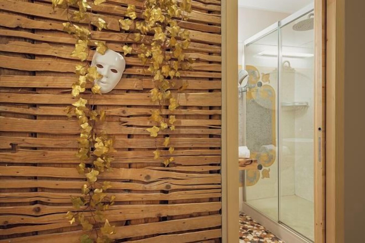 A room with a wooden slatted wall and a glass shower enclosure.