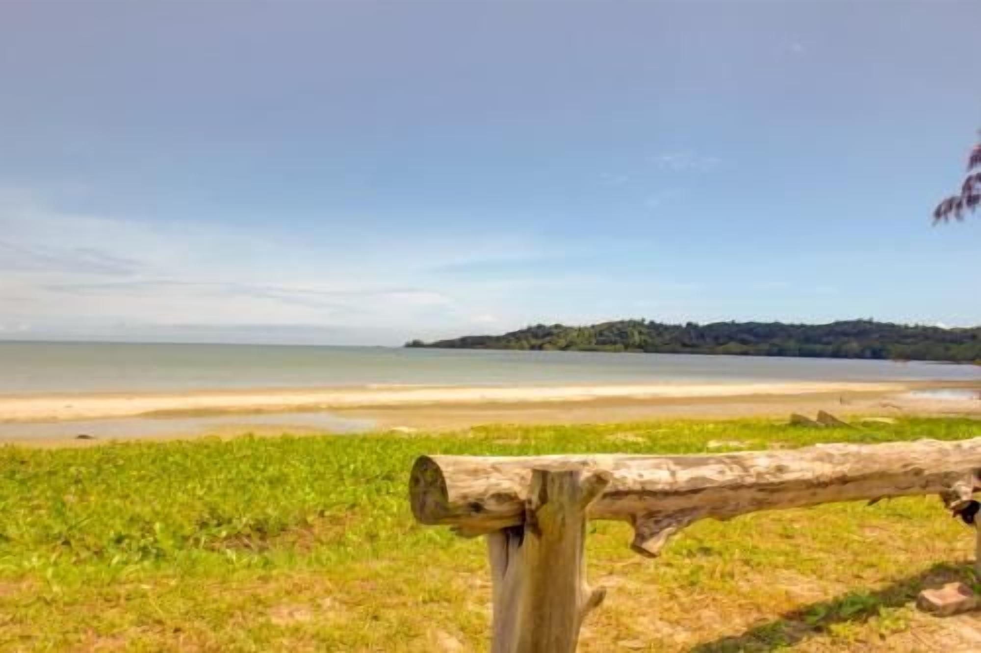 A beach view with a wooden fence in the foreground and a distant shoreline.
