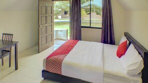 Quarto de hotel com uma cama, uma escrivaninha e uma janela com cortinas.
