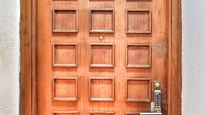 Une porte en bois dotée d’un clavier pour ouvrir la serrure et d’un panneau vert indiquant la sortie de secours, placé au-dessus.