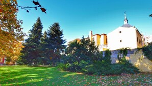 Un bâtiment à la façade blanche, surmonté d’un dôme, entouré d’une pelouse bien entretenue et d’arbres.