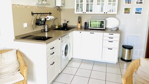 Une cuisine compacte équipée d’un lave-linge, d’un four à micro-ondes et d’un évier.