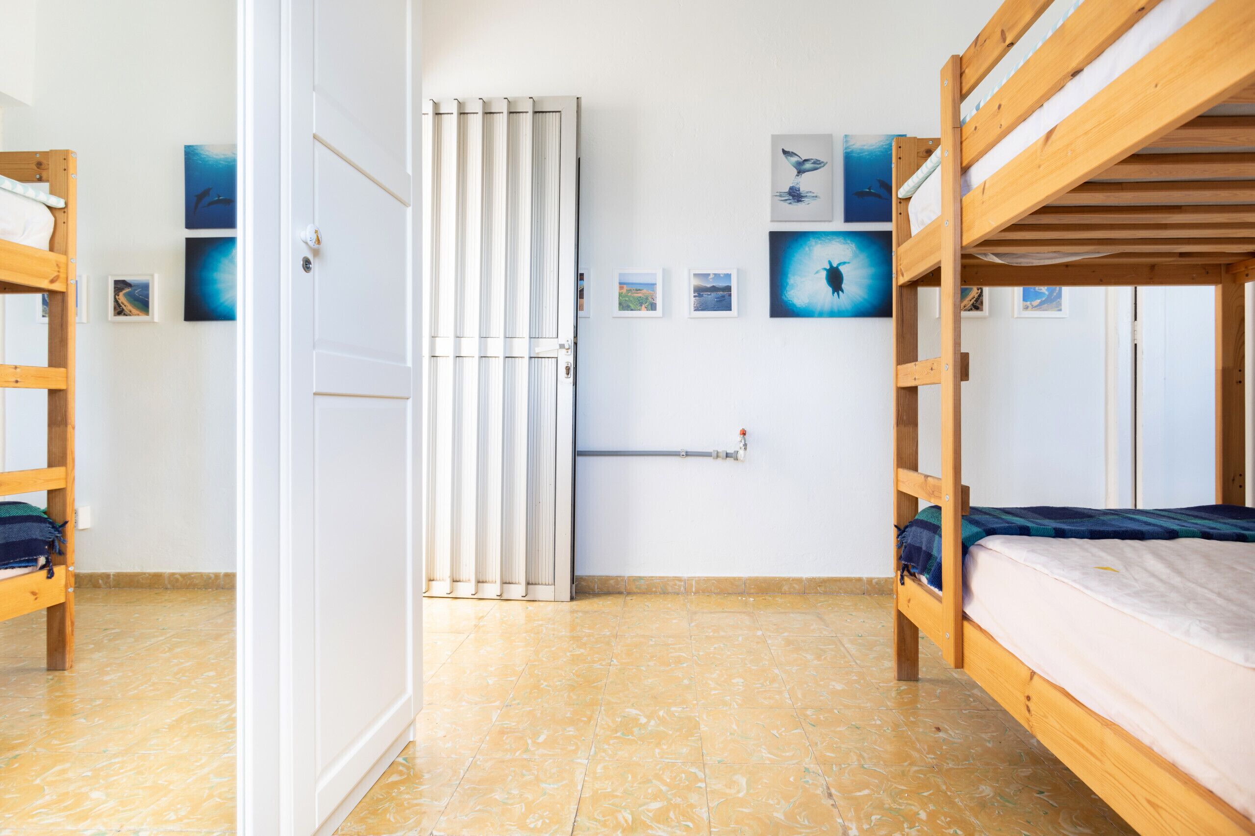 Una habitación con dos literas, un radiador y varias fotografías enmarcadas en la pared.