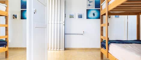 Una habitación con dos literas, un radiador y varias fotografías enmarcadas en la pared.