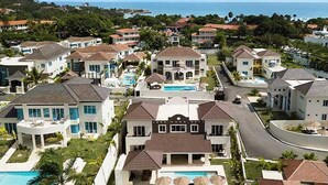 A residential area with multiple houses, a swimming pool, and a view of the ocean. - Soak up sun & fun at a 6-bed villa in the Dominican Republic resort on the ocean (Cofresi)
