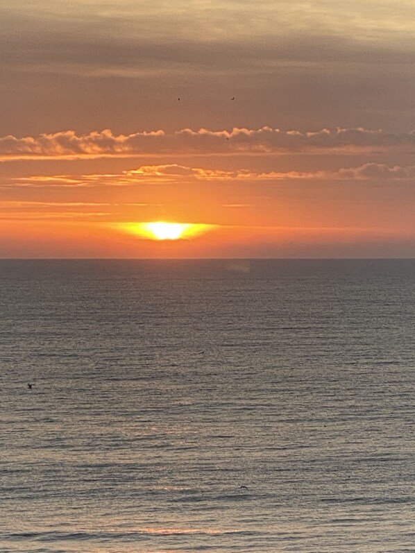 A sunset over a calm sea with a clear horizon.