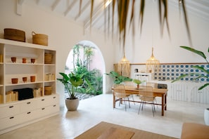 Un comedor amplio con una mesa y sillas de madera, rodeado de estanterías blancas con libros y cestas.