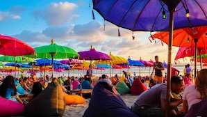 Uma praia com guarda-sóis coloridos e espreguiçadeiras.