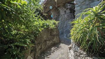 Un estrecho sendero de piedra que conduce a un rústico edificio de piedra con un reloj en la pared.