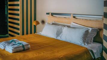 Ein Bett mit weißer Bettwäsche, einer gestreiften Wand und einer Lampe.