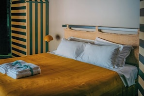 A bed with white linens, a striped wall, and a lamp.