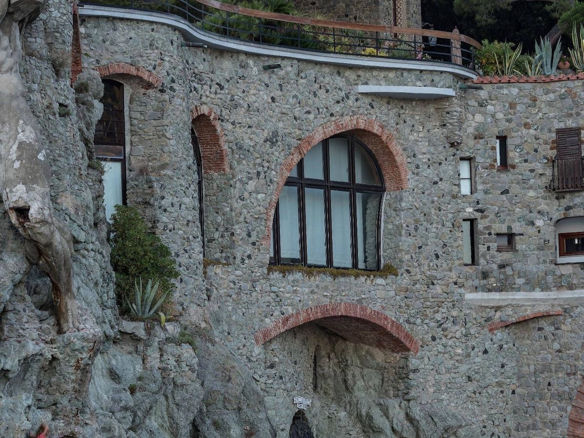 Un bâtiment en pierre doté de fenêtres en arc de cercle et d’un balcon.