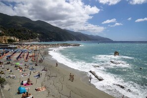 A beach with umbrellas, people, and rocky coastline.