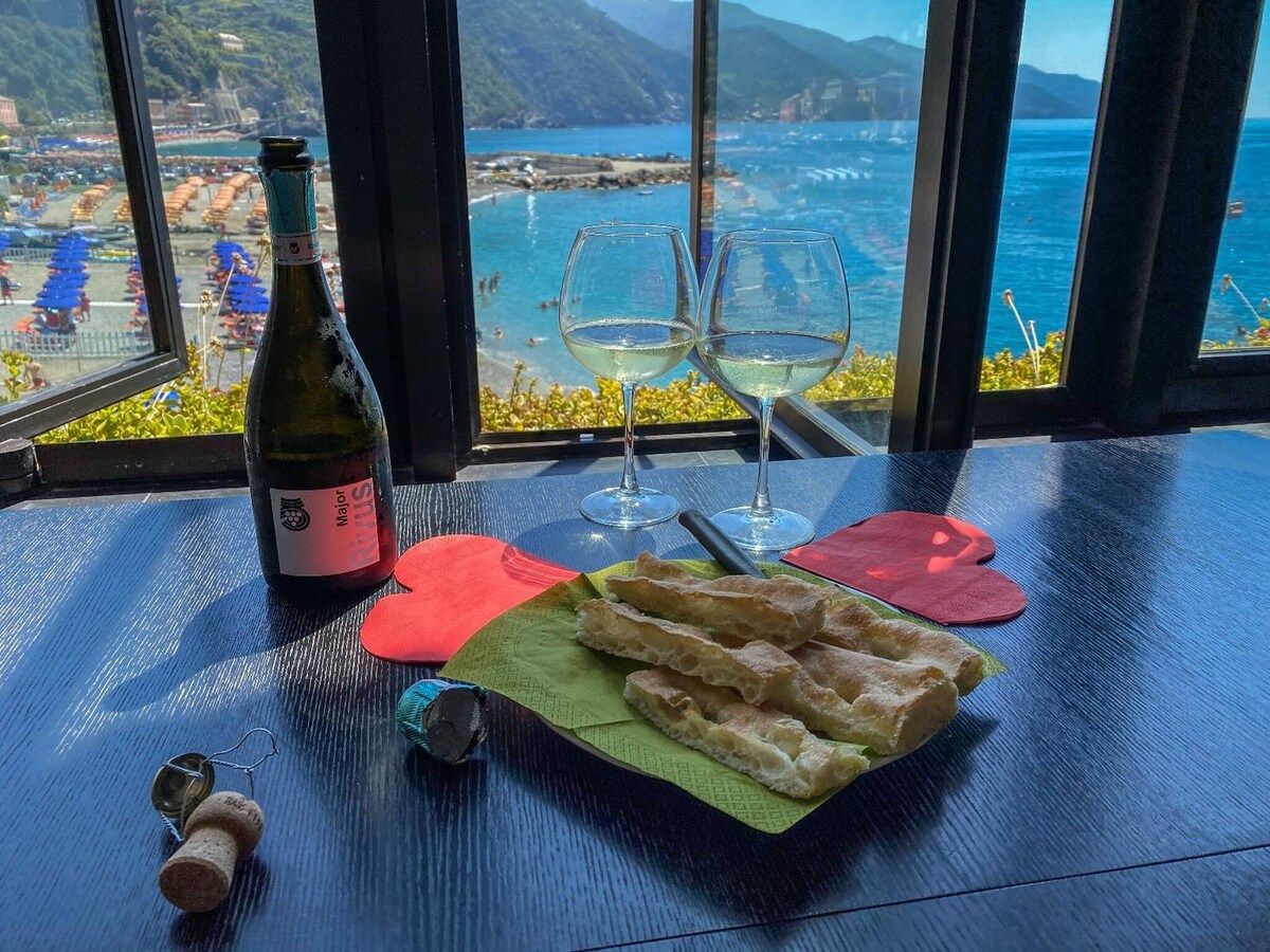 Une table avec une bouteille de vin, deux verres et une assiette de pain.