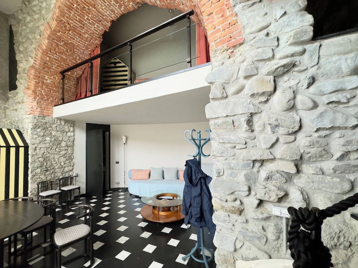 Une pièce avec un sol à carreaux, une table à manger avec des chaises, un canapé et un mur en pierre.