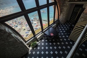 Ein Zimmer mit großem Fenster zum Strand, mit Fliesenboden und Tisch mit Stühlen.