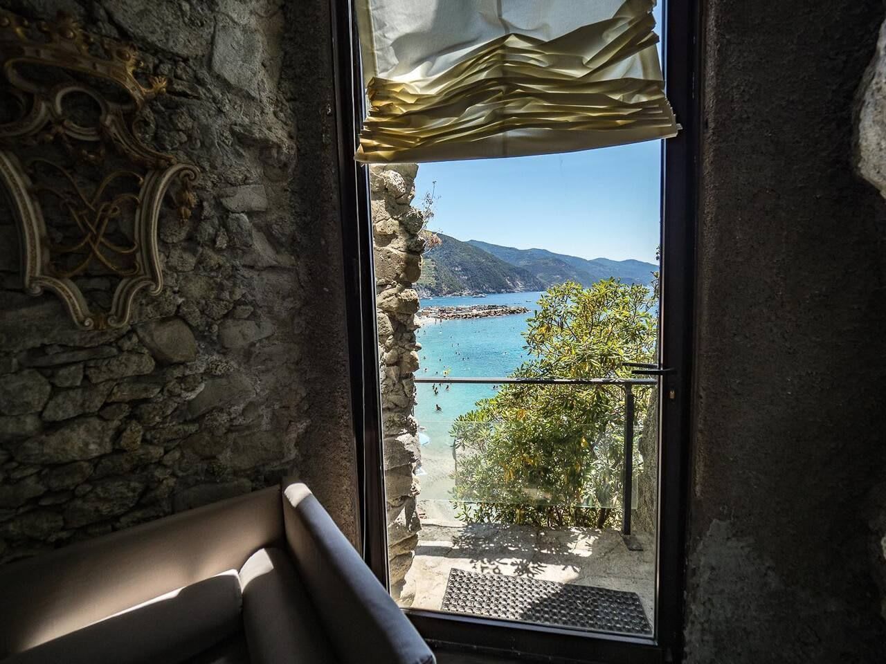 A stone wall with a window overlooking a coastal view.