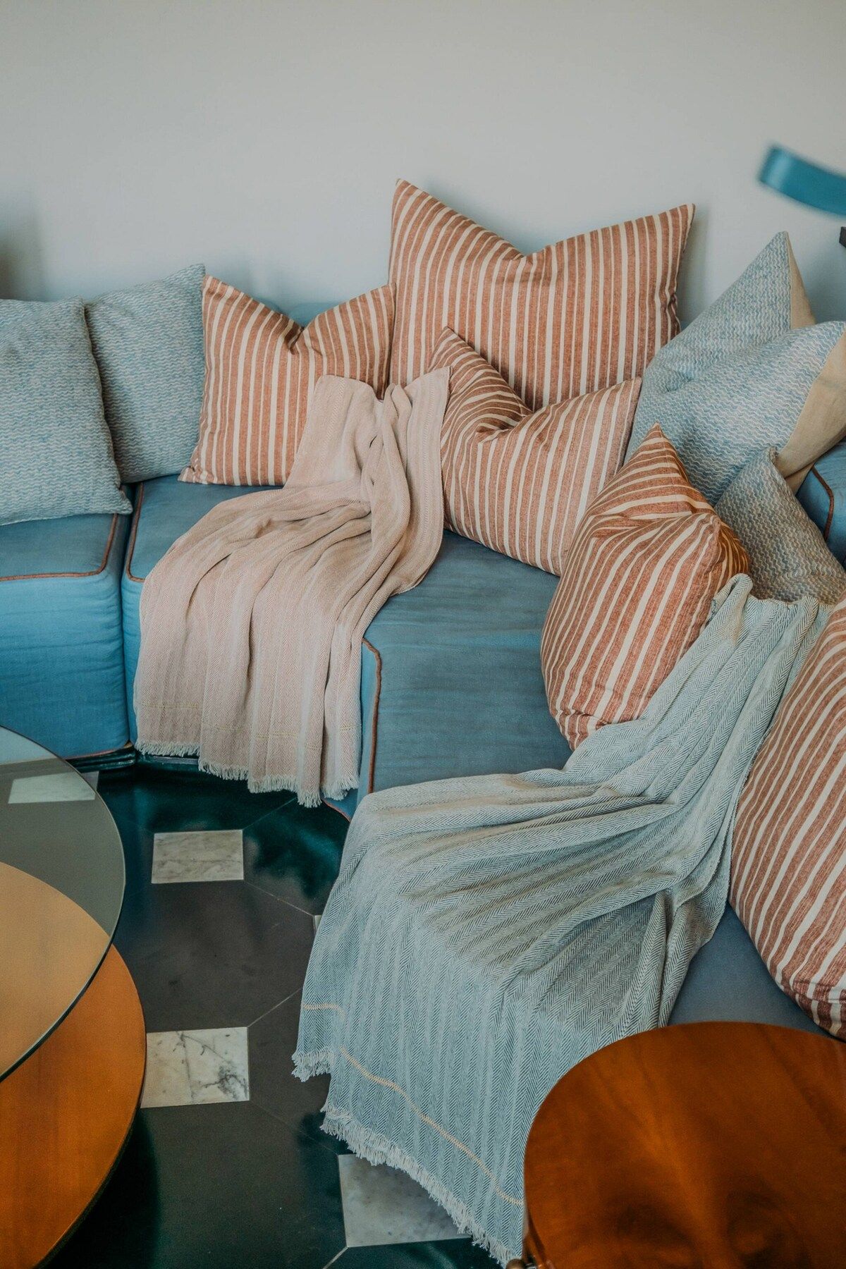 Ein modernes Wohnzimmer mit einem blauen Sofa, gestreiften Kissen und einer hellblauen Decke.